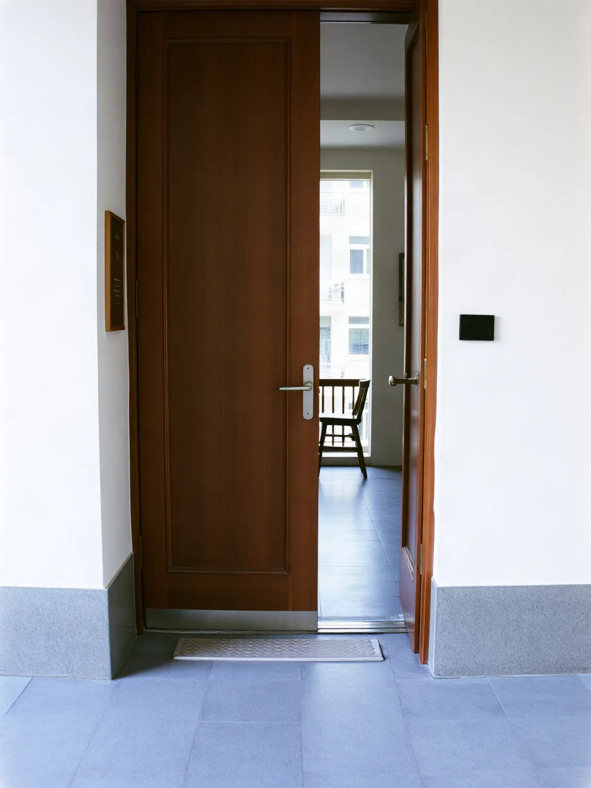 Porta d'ingresso di un appartamento in legno scuro vista dal pianerottolo